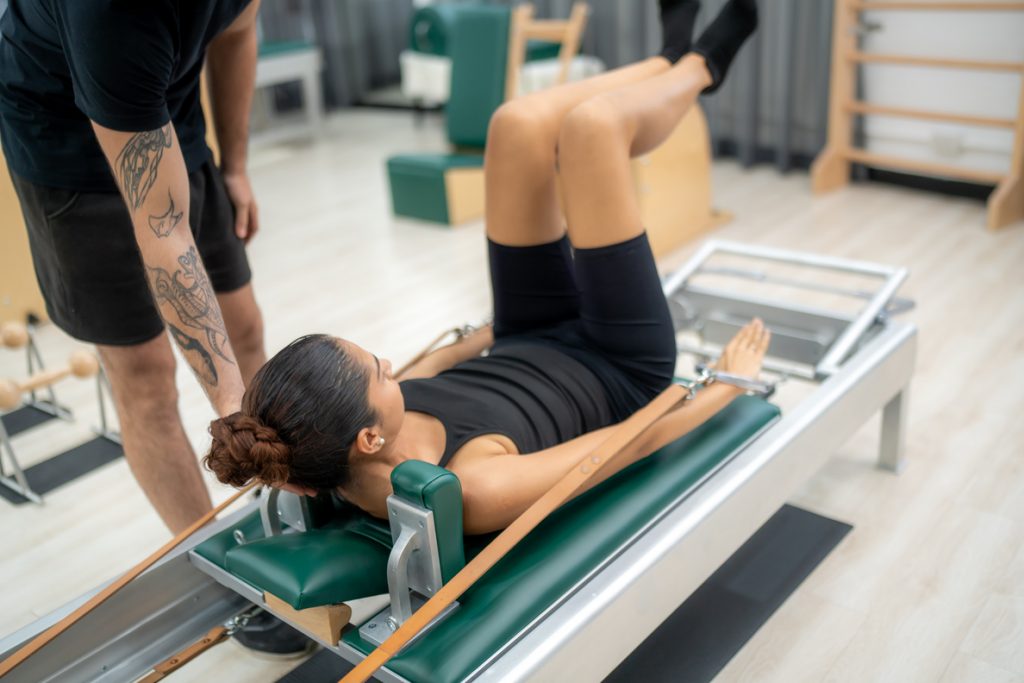 woman doing pilates on a machine | Featured image of the Mental Health Benefits of Pilates blog page
